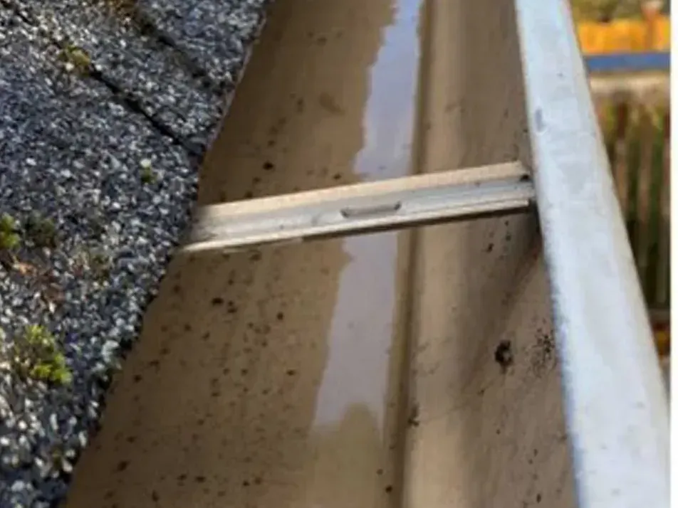 After cleaning: the same gutter cleared down to the trough, water standing in it