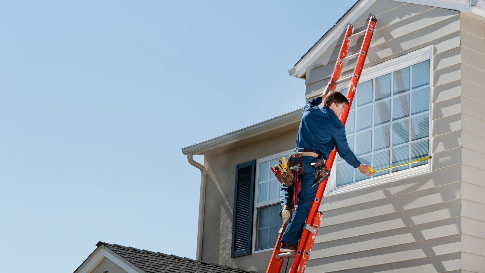 An extension ladder set to the upper storey of a house, up at the eave and gutter line